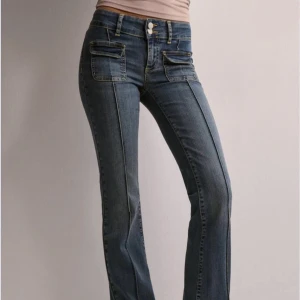 Blå bootcut jeans med fickdetaljer - Snygga blå jeans med bootcut passform och låg midja. Framtill finns två fickor med lock och dubbla knappar i midjan. Är slutsålda på hemsidan!. Skriv vid frågor❤️