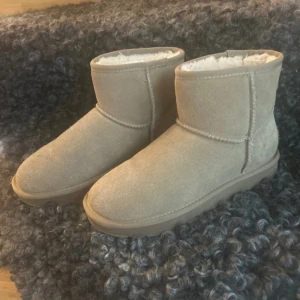 Beigea ugg  - Mysiga Ugg liknade skor i beige mocka med mjukt vitt foder på insidan. Använda nån gång bara! Nypris 599