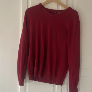 Vinröd tröja från dressman - Säljer en vinröd tröja från Pima Cotton i storlek L. Tröjan har v-ringad hals och är långärmad med ribbade muddar vid hals, ärmslut och nederkant. Materialet är mjuk bomull som känns skönt mot huden. Perfekt för dig som gillar enkel och stilren design.