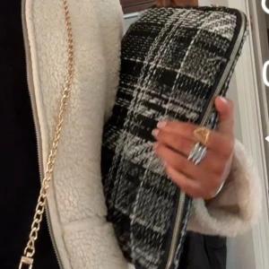 Rutig svartvit data fodral - Snygg kuvertväska i svart och vitt med rutigt mönster. Väskan har en dragkedja upptill och är gjord i ett grovt tygmaterial som ger en cool och trendig känsla. Perfekt att bära under armen för en stilren look. Har dock lite slitningar, men inget man tänker på.