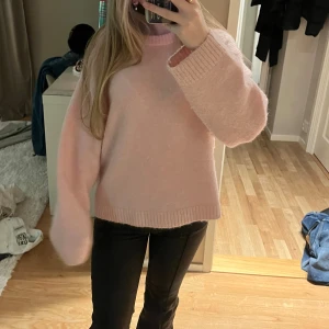Ljusrosa stickad tröja från Gina Tricot - Supermysig ljusrosa stickad tröja från Gina Tricot i ullblandning. Tröjan har en loose passform, breda ärmar och ribbade muddar vid hals, ärmslut och nederkant. Perfekt för lager-på-lager under kyliga dagar.
