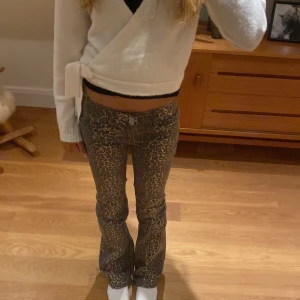 Leopardmönstrade bootcut jeans - Säljer ett par snygga jeans med leopardmönster i bruna och beige toner. Byxorna har bootcut passform och låg midjade.Perfekt för dig som vill sticka ut med coola detaljer.