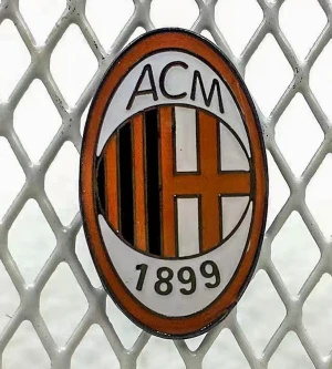 AC Milan pin i metall - Snygg oval pin med AC Milan-logga, perfekt för dig som älskar fotboll. Märket har svart, röd, vit och guld färg med randigt mönster och årtalet 1899. Tillverkad i metall med klassisk nål på baksidan. Grym accessoar för jackan eller väskan!
