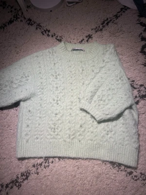 Ljusgrön stickad tröja med pärlor - Superfin ljusgrön stickad tröja från Zara med kabelstickat mönster och pärldetaljer över hela tröjan. Tröjan har en loose passform, ribbad kant och trekvartsärm. Perfekt för dig som gillar mysiga och snygga detaljer. Skulle säga att tröjan är lite grönare än på bilderna. Jag är öppen för prisförslag!🥰