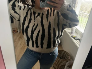 Beige och svart zebramönstrad tröja MNG - Säljer en beige och svart stickad tröja från MNG i storlek M. Tröjan har ett coolt zebramönster, rund hals och ribbade muddar vid ärmslut och nederkant. Perfekt för dig som gillar djurmönster och vill ha en skön, loose passform.