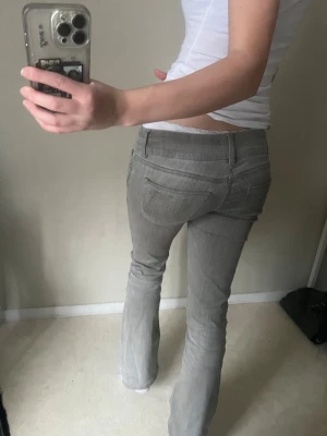Grå bootcut jeans med låg midja - Säljer ett par gråa jeans med snygg bootcut och låg midja. Jeansen har klassiska fickor både fram och bak, och är tillverkade i ett mjukt jeansmaterial som sitter skönt. Perfekt passform för dig som gillar en lite retro vibe.