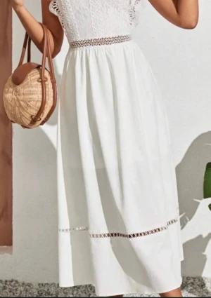 Vit långklänning med spetsdetaljer - Superfin vit långklänning med spets upptill och dekorativa spetsband i midjan och längs kjolen. Ärmlös modell med romantiska detaljer och lätt, flowy kjol. Perfekt för dig som gillar en feminin och somrig stil. Materialet känns som bomull med inslag av spets.
