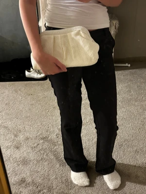 Vit kuvertväska - Snygg vit kuvertväska med struktur och mjuk form. Väskan har ett stilrent och enkelt utseende med diskreta veck framtill. Perfekt att hålla i handen och passar till många olika outfits.