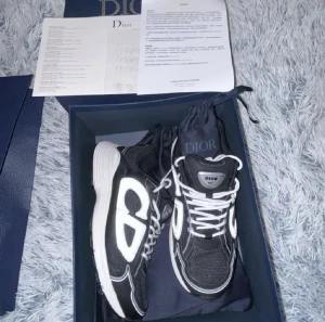 Dior skor - Snygga svarta Dior sneakers med stora reflekterande CD-detaljer på sidorna. Skorna har vit sula, vita snören och är tillverkade i en mix av mesh. Skorna är helt nya och aldrig använda 