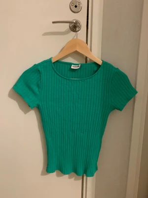 Grön t-shirt  - En grön tshirt med kroppsnära passform i ribbat material från vero moda i storlek Xs, aldrig använt. Snygg stilren tröja som passar att ha på till olika tillfällen💚