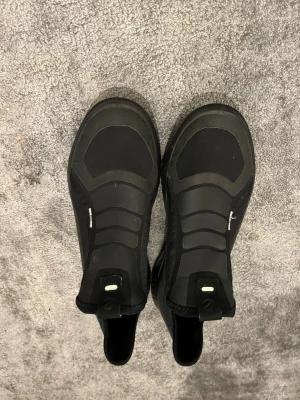 Svarta ECCO ST.1 sneakers - Säljer ett par svarta ECCO ST.1 sneakers med modern design och elastiska paneler. Skorna har platt sula med Phorene-dämpning och detaljer i syntetmaterial. Rund tå och smidiga dragflikar baktill för enkel påtagning. Perfekt för dig som gillar stilrena och sportiga skor.