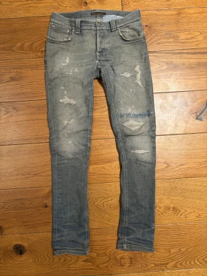 Nudie jeans - Intresse koll på mina nudie jeans, de är i modellen grim tim och har en ovanlig färg och custom slitningar lagade hos nudie jeans, jeansen är i bra skick komm med bud och hör av dig vid minsta fråga. Waist = 38,5 cm - innerbenslängd = 77cm