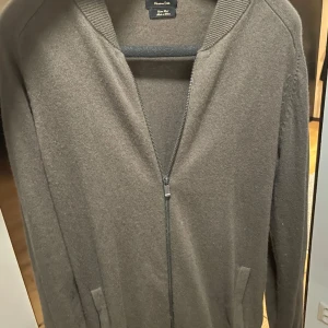 Mörk Grön kofta från Massimo Dutti - Säljer en stilren mörk grön kofta från Massimo Dutti i bomull och ull. Koftan har en dragkedja framtill och långa ärmar. Perfekt för kyligare dagar. Använd, ny pris 800 vid snabb affär kan priset sänkas 