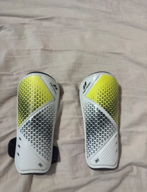 Pro Touch benskydd i vitt och gult - Säljer ett par benskydd från Pro Touch i storlek M.  Helt nya! 