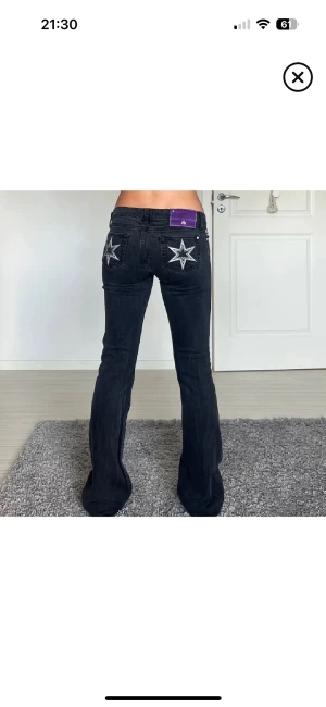 Victoria Beckham bootcut jeans  - Snygga svarta jeans från Victoria Beckham med bootcut passform och låg midja. Baktill finns broderade vita stjärnor på bakfickorna och ett lila patch vid linningen. Jeansen är i klassisk denim och har en cool, unik look.