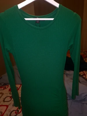 Grön ribbad långärmad klänning - Snygg grön ribbad klänning från Bik Bok med lång ärm och rund halsringning. Modellen är figurnära och har en kort längd som framhäver siluetten. Perfekt för dig som gillar enkel men stilren design med lite edge.