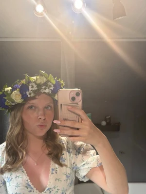 Blommig volangklänning med puffärm - Söt kortklänning med blått blommönster på vit botten, volanger och puffärmar. Djup v-ringning och omlottkänsla framtill. Perfekt för sommarens tillfällen. Materialet känns lätt och luftigt.