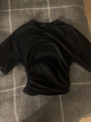 Svart kortärmad topp  - Säljer en svart topp den är tight vid magen och är pösigare upptill.