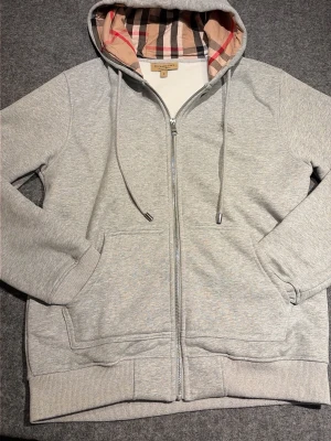 Grå zip-hoodie från Burberry - Snygg grå hoodie från burberry, väldigt bra skick då ja använt den väldigt lite. Priset är inte hugget i sten 