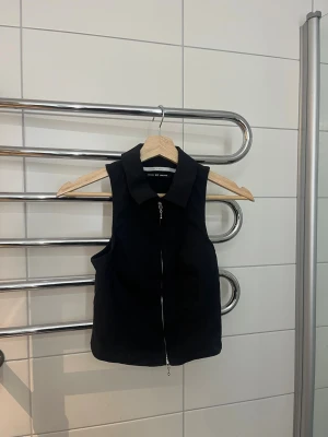 Svart väst/ festtopp ifrån Urban outfitters🪩 - Snygg svart väst från Urban outfitters med krage och dragkedja framtill💋Storlek xs!