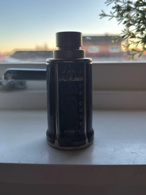 Hugo Boss Bottled Magnetic EdT 80ml kvar - Snygg parfymflaska från Hugo Boss, modellen Bottled Magnetic. Flaskan är mörkblå med silverdetaljer och har en robust, cylindrisk form. Perfekt för dig som gillar stilrena och moderna dofter.