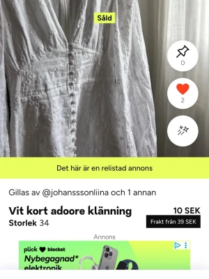 Vit kort klänning från Adoore - Supersöt vit kort klänning från Adoore med dekorativa knappar framtill och diskret broderat mönster. Klänningen har v-ringning och långa ärmar, perfekt för en fräsch och stilren look.