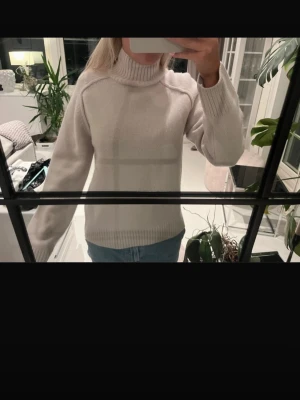 Beige stickad polotröja - Mysig beige stickad polotröja med ribbade muddar och hög krage. Tröjan har en rak passform och långa ärmar, perfekt för kyliga dagar. Enkel och stilren design som passar till det mesta. En defekt inte testat att tvätta men kommer gå bort. Köpte för 1500kr från hm 