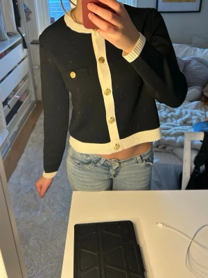 Svart-vit cardigan från Zara - Trendig svart cardigan från Zara med vita kontrastdetaljer vid krage, knappslå, ärmslut och nederkant. Guldknappar framtill och två dekorativa bröstfickor. Pris kan diskuteras men ordinarie pris var 549💕