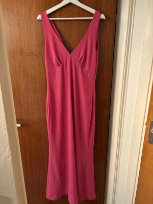 Rosa balklänning med djup rygg - Säljer en snygg rosa balklänning med djup v-ringning fram och draperad öppen rygg. Klänningen har en slits baktill och är ärmlös med breda axelband. S/M