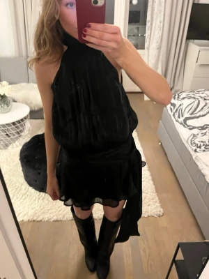 Svart satinklänning Gina - Säljer den snyggaste svarta satinklänningen med halterneck och knytning i midjan från Gina. Den är endast använd en gång och därför i superbra skick. Passar superbra till mer festligare tillfällen. Storleken är XS men jag skulle säga att den passar allt från XS-S beroende på kroppstyp och hur man vill att den ska sitta. Perfekt både till boots och ballerinaskor.  Går även att välja hur hårt man vill knyta den i midjan. Tveka inte att höra av er vid frågor och lägg gärna prisförslag! 