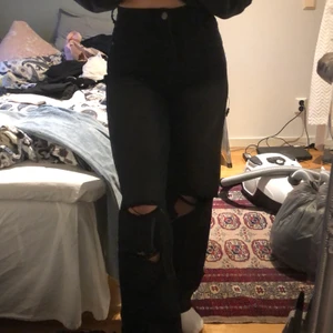 Boohoo svarta högmidjade jeans storlek 38  - Högmidjade jeans med två hål på vänster ben och ett hål på höger ben. Storlek 38, modellen är 169 
