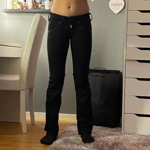Svarta lågmidjade Lee jeans i modellen Cade. Det är svarta jeans som är lite bootcut i modellen, det har lila detaljer i bak och väldigt fina. Ungefär XXS-XS 