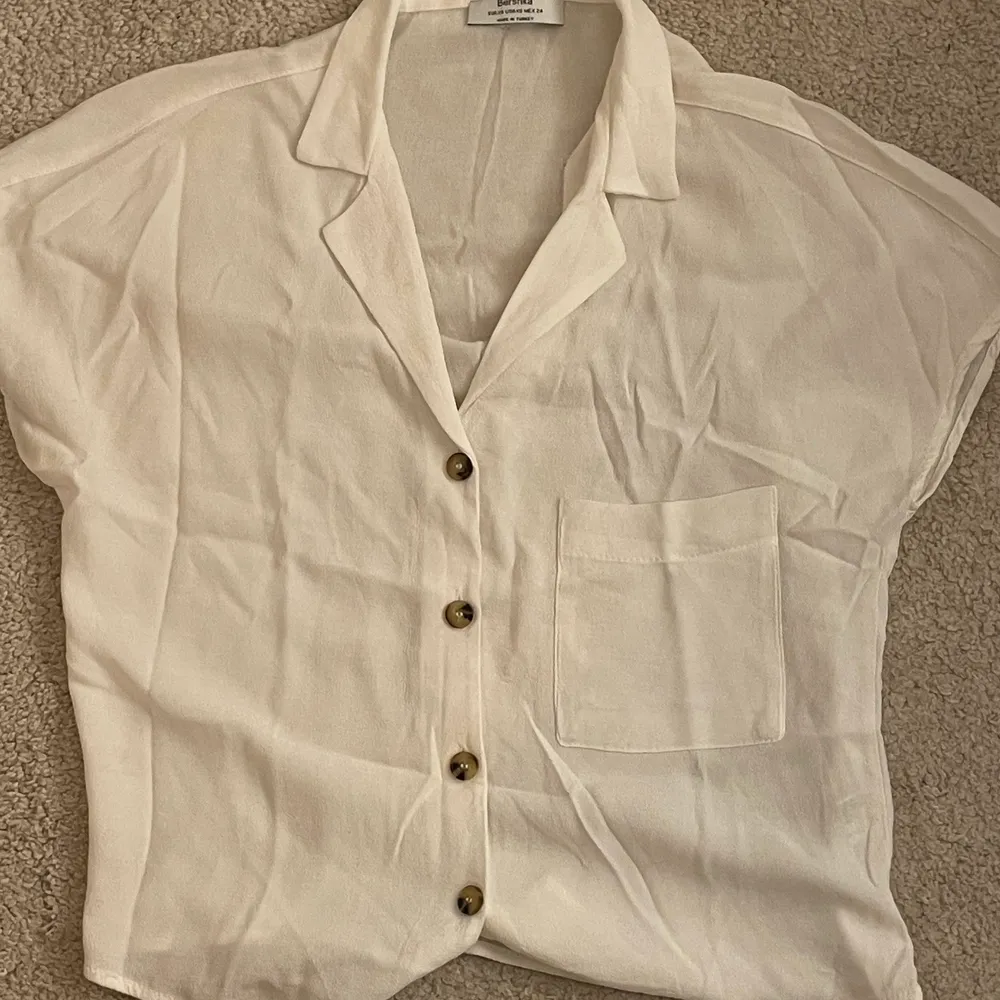 En vit/krämvit kortärmad blus eller skjorta från berska. Inte särskilt använd och bra skick. Den passar mig som är s/m trots att den är en xs💝. Toppar.