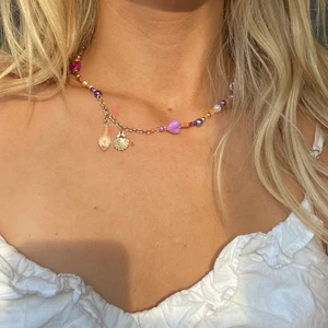 Handgjort halsband - Handgjort halsband i orange och lila, samt en guldig kedja och fina hängen. Skriv för mer bilder och mått! Frakt är inräknat i priset!