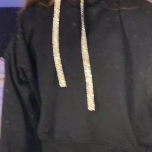 Svart hoodie.  - Svart hoodie med glittriga snören. Köpte här på Plick också. Är i bra skick. Säljer på grund av att jag inte använder den så ofta. Köparen står för frakten. Kontakta mig ifall du har några frågor, mer bilder, intresserad mm (: 