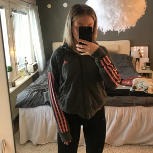 zip hoddie från adidas - grå hoodie med dragkedja från adidas med rosa/koral streck. nypris 699kr. som ny. 66kr för frakt tillkommer:)
