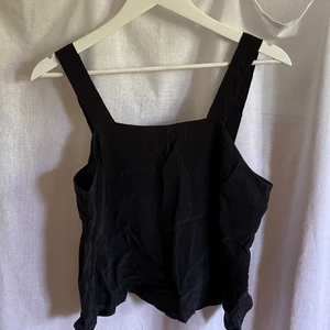 Svart festlinne - Svart supersnyggt linne med breda band, i ett lite exklusivt svart tyg. Perfekt för höstens festliga tillfällen. I perfekt skick, som ny!!