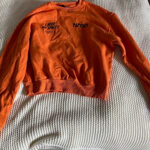 Detta är en orange tröja från H&M med Nasa printer över brösten. Sällan använd!