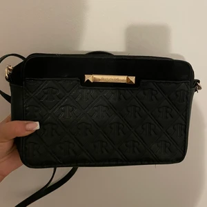 River Island väska - Väska köpt från River Island med guld detaljer. Den är i både mocka och skin. Remsan är avtagarbar vilket gör att den kan användas som en axelväska men även som en större handväska.