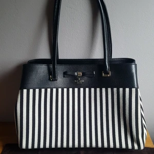 Kate Spade väska - Kate Spade väska köpt på Century 21 i New York. Ursprungsvärde ca 2700 kr. Är i bra skick, har en liten slitning i ena hörnet men ser i övrigt ut som ny. Dustbag ingår! Mått: 38 cm bred, 26 cm hög och 13 cm djup. DMa om du är intresserad! :)