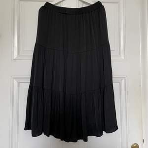 En supersöt svart kjol med volanger från Gina. Storlek L och stretchig midja. Midi längd. Perfekt till sommaren. Använd ett fåtal gånger. Frakten ingår i priset ✨