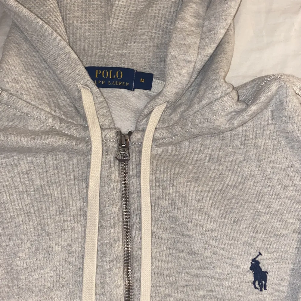 Grå Ralph Lauren tröja med dragskeddja. Vita snören använder aldrig nyköpt 1500 säljer för 500 ink frakt inga fläckar och smuts helt ren passar både M/S skit fin😊 skriv om du e intresserad🥰. Tröjor & Koftor.