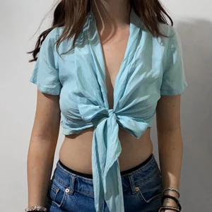 Blå knytblus - Blå knytblus i silkes material. Köpt på secondhand men endast använd utav mig 1 gång. Väldigt bra skick men saknar lapp om märke och storlek, jag skulle säga att den passar mellan XS-M! Stryks innan den skickas!