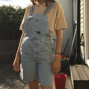 Jeans-hängselbyxor  - Jättesnygga hängselbyxor i jeans. Många fickor, band, justerbara hängslen och några utplacerade märken finns med och gör plagget coolt och på modet. Mycket gott skick och passar alla olika kön! 