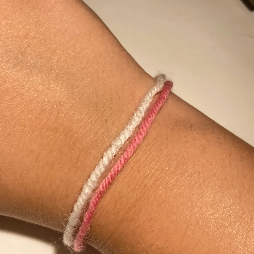 Vit&rosa armband gjord av garn, man får knyta den själv! . Accessoarer.