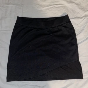 Kjol - En svart tygkjol med en liten volange. Stl 134/140 