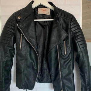 Chiquelle Moto Jacket Black - Snygg Mc-inspirerad jacka i läderimitation med quiltade detaljer på axlar och i ärmslut. Två fickor med dragkedja framtill. Reglerbara bälten på sidorna. Knappt använd, nypris 699kr