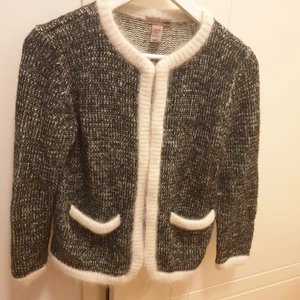 Chanellik kofta - Gråmelerad kofta med vita kanter, väldigt Chanel. Mix av bla ull, angora och mohair. Storlek 36 från H&M, passar även storlek 38. Som ny. 