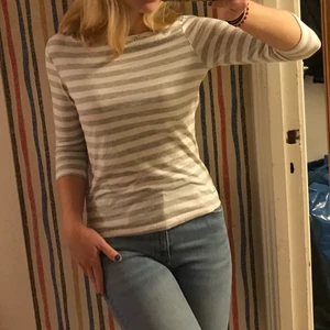 Randig tröja - Fin vitgrå/randig tröja. Lite trekvartsmodell i armarna och rakt skuren hals. Passar perfekt till smycken som ligger fint utanpå tröjan. Bara använd några få gånger,så gott som ny. Så om du inte redan hoppat på trenden, passa på!🤪