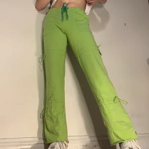 Gröna vintage mjukisbyxor y2k störning - Gröna 2000-tals vintage lågmidjade stretchiga mjukisbyxor med fickor och snörning i midjan, vid låren och vid vaderna 🧩 Dessa byxorna är så så sköna och sitter otroligt! De ger den bästa 2000-tals viben och är ett så bra alternativ för den som letar efter mer unika statement mjukiskläder! Alla detaljer med fickorna på utsidan och snörningen på benen gör de till one of a kind! Midjemåttet är 78 cm och benlängden är 94 cm!